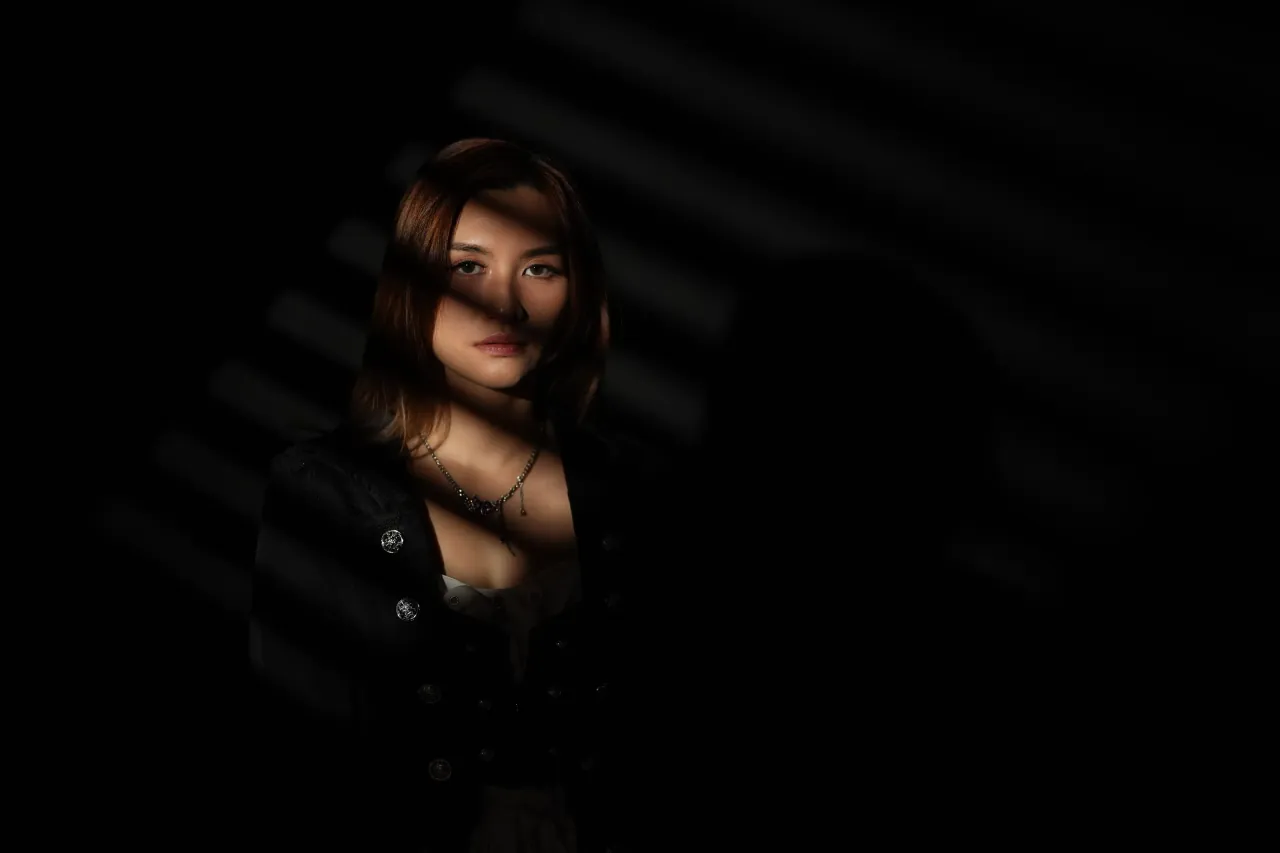 Hard striped light across the eyes — high-contrast portrait study