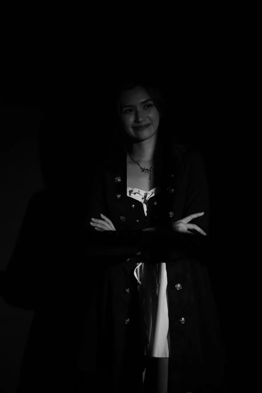 Arms crossed, low-key studio portrait against black