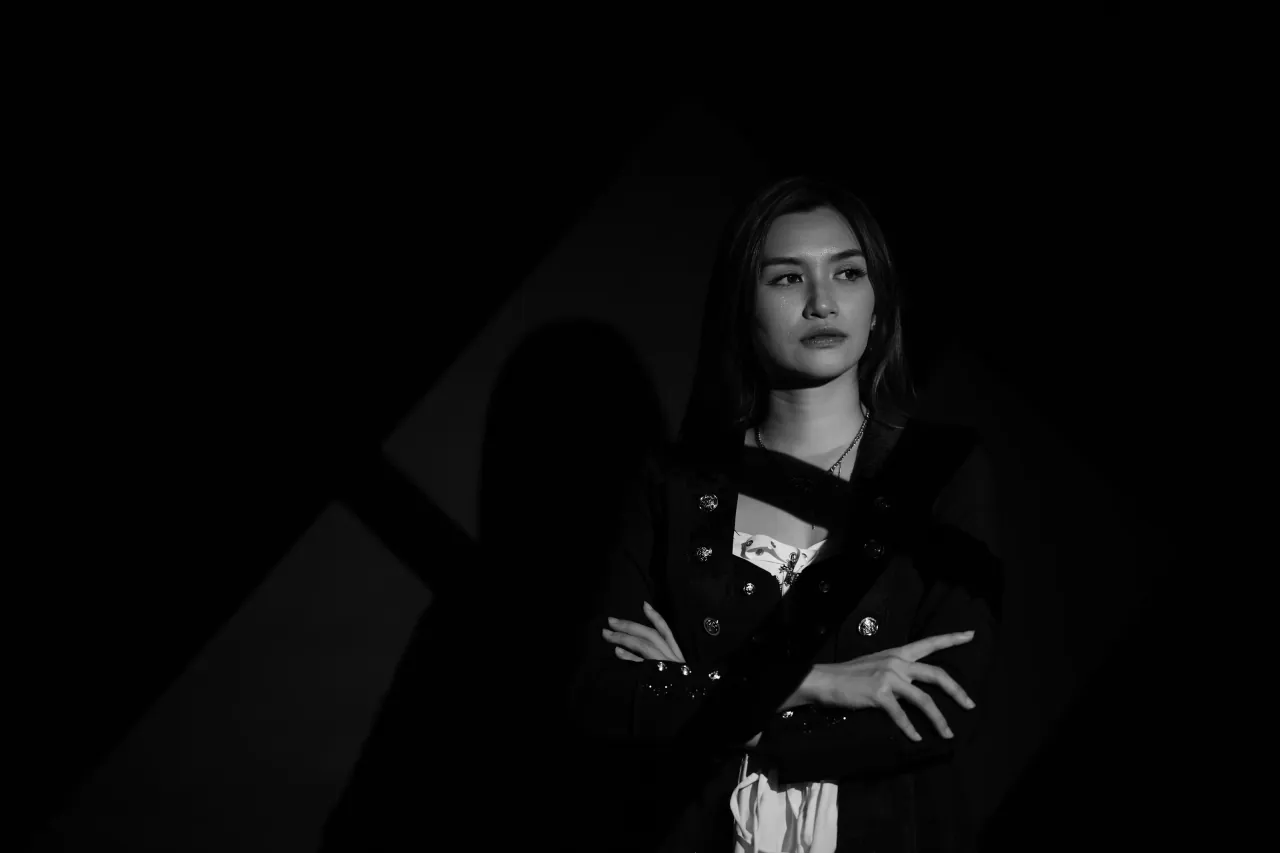 Wide low-key frame with arms crossed — editorial crop