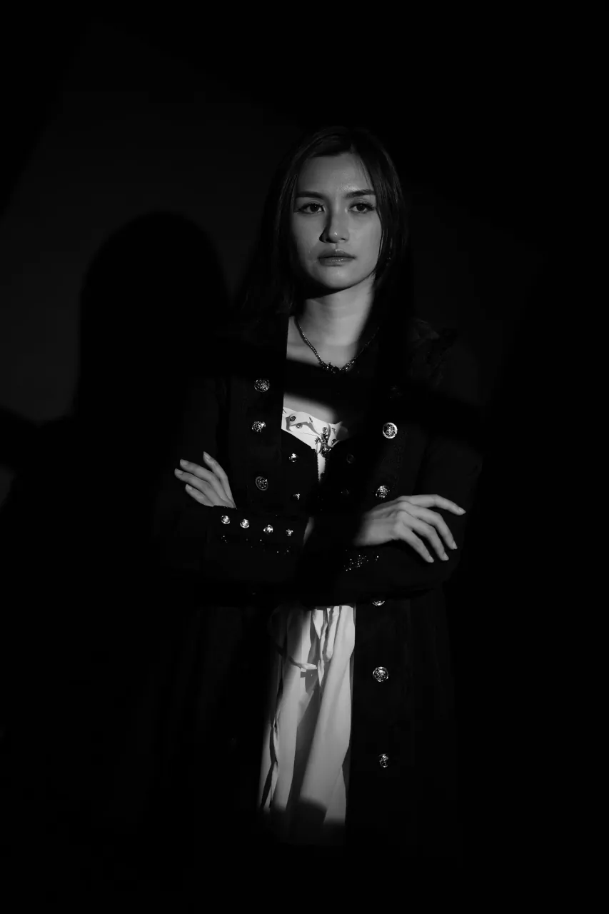 Arms crossed and lit from the side, jacket hardware catching light