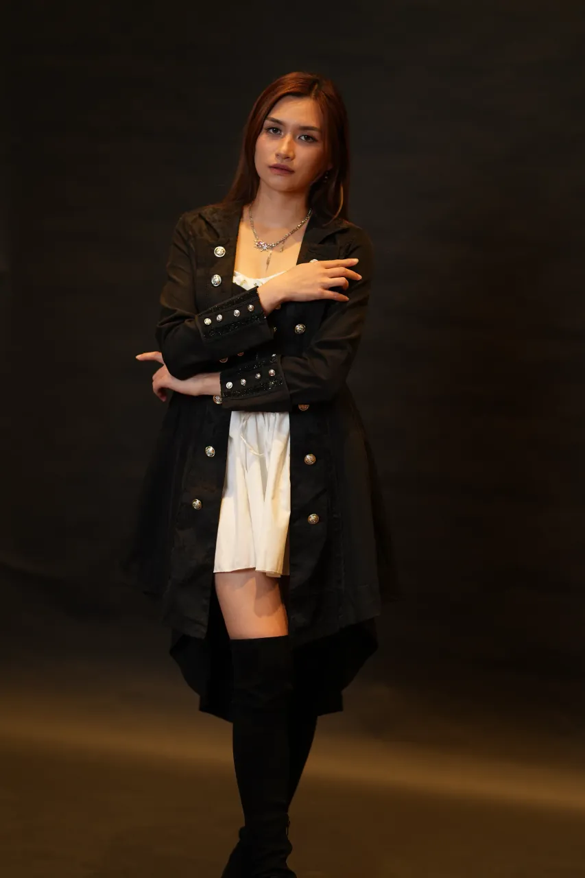 Full-length standing portrait against a warm studio backdrop
